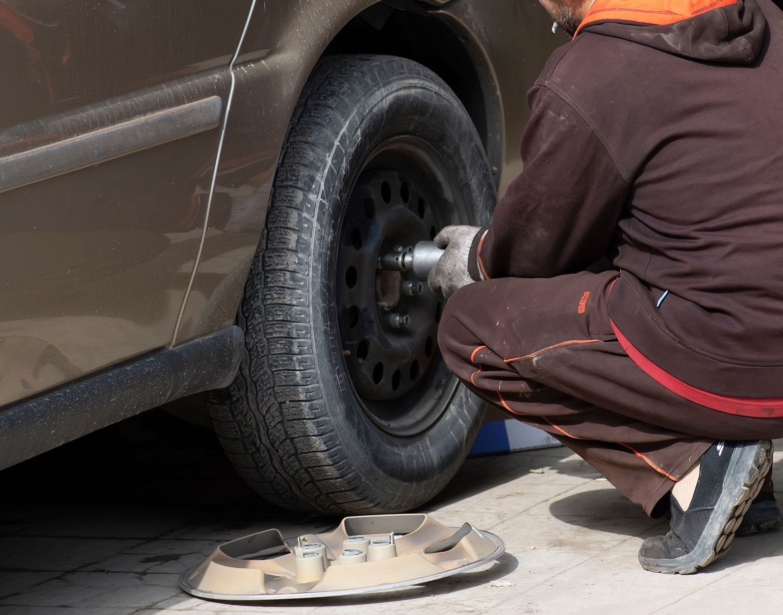 A mechanic working on a car tire, changing it in an auto repair shop.